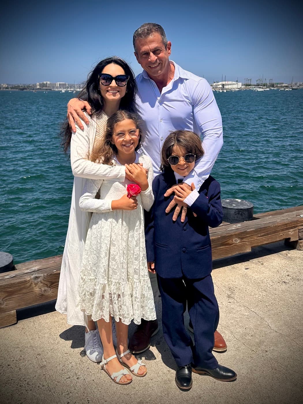 The Rezende family — Maria Luiza, Luciano, and their two children — by the water in San Diego